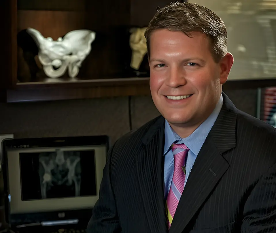 A man in suit and tie standing next to a fireplace.