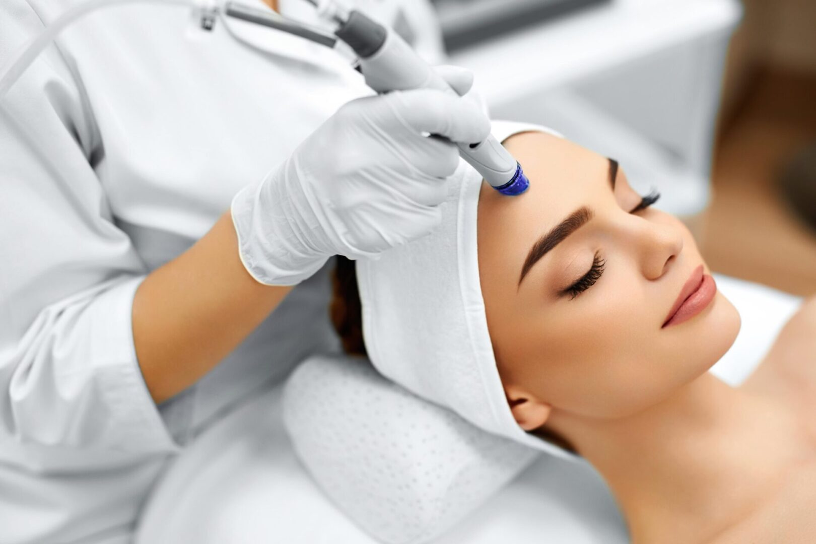 A woman getting her face cleaned by an esthetician.