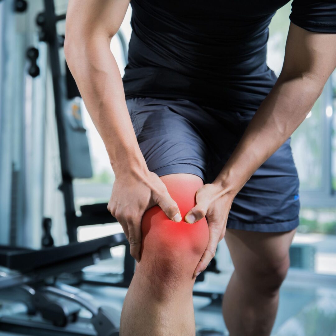 A man holding his knee in the gym