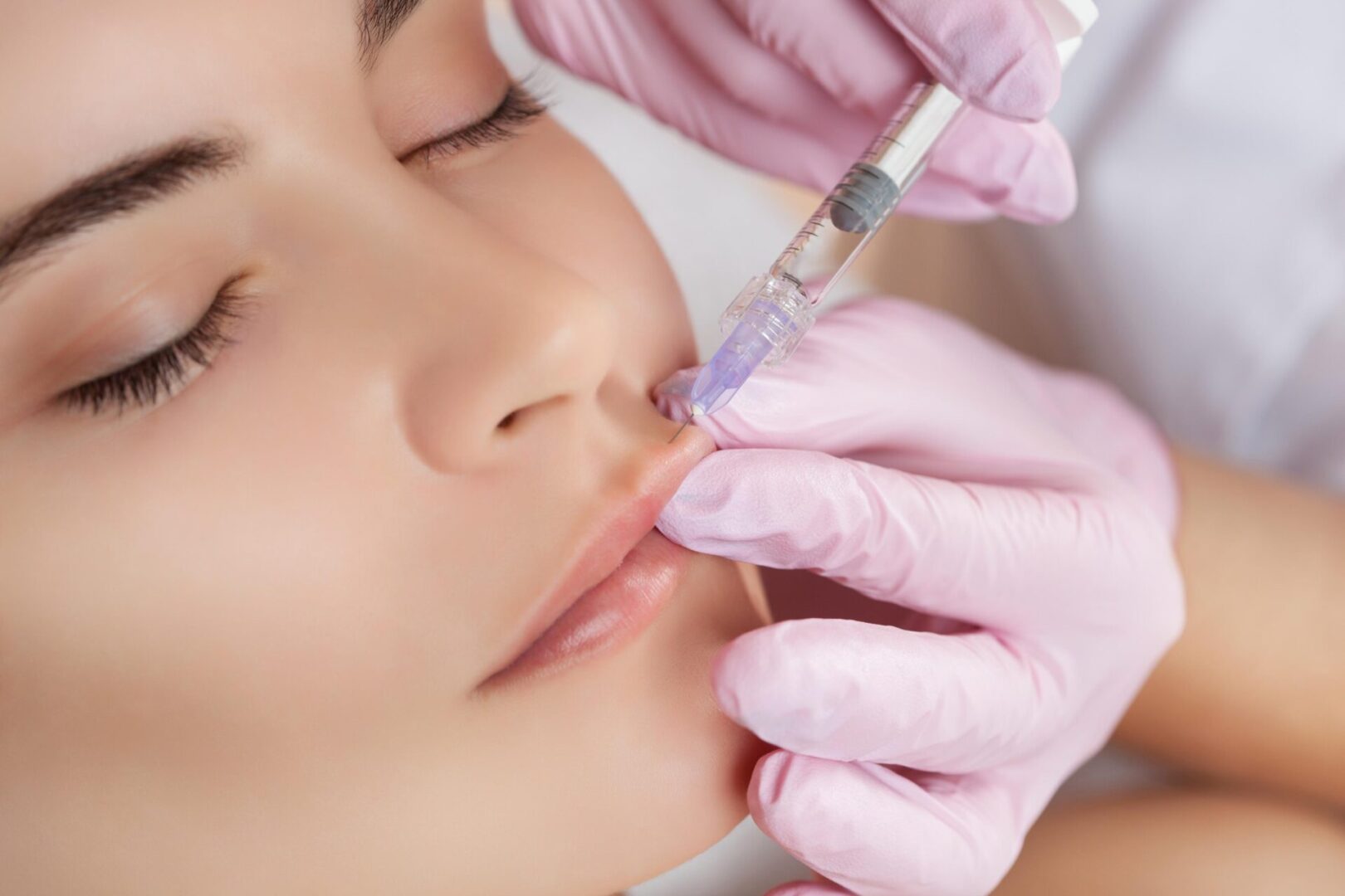 A woman getting her lips waxed by an esthetician.