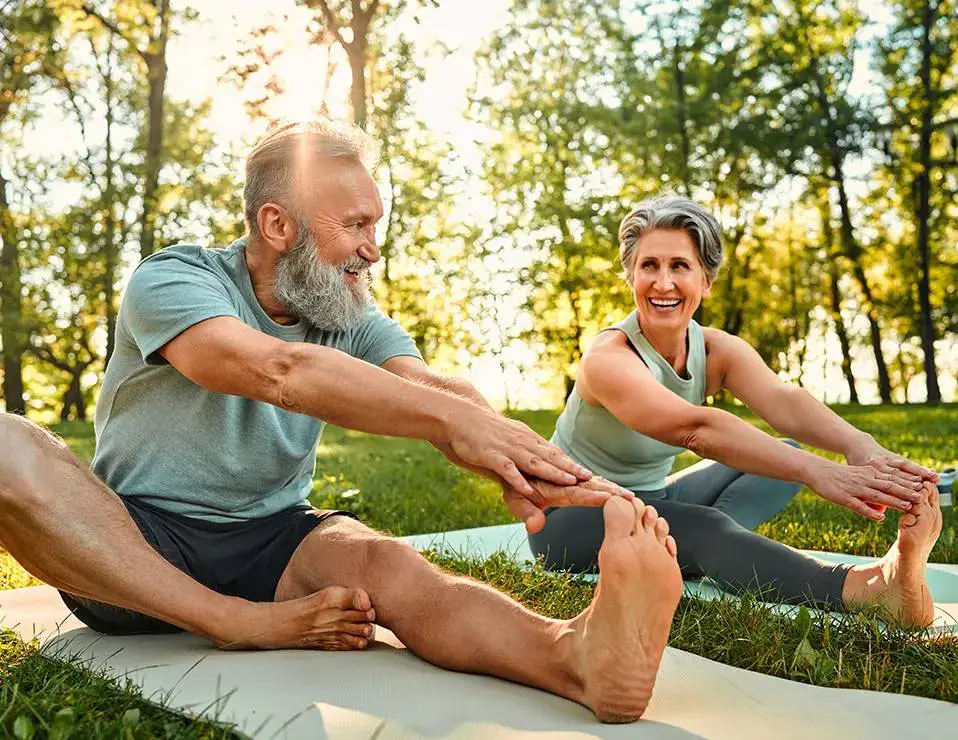 Senior couple stretching outdoors in park.